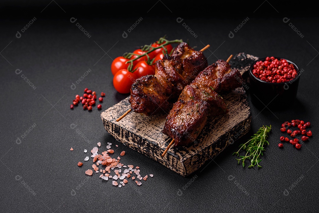 Deliciosos espetos de frango, peru ou porco grelhados com sal, especiarias e ervas no fogo sobre um fundo escuro de concreto