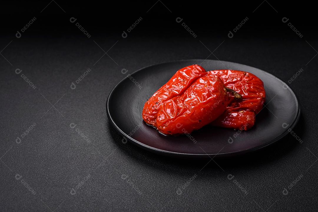 Deliciosos pimentões grelhados com especiarias e ervas em um fundo escuro de concreto