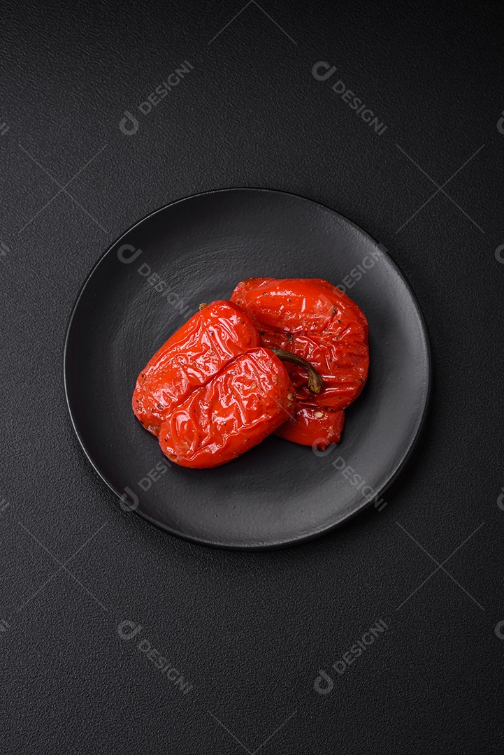 Deliciosos pimentões grelhados com especiarias e ervas em um fundo escuro de concreto