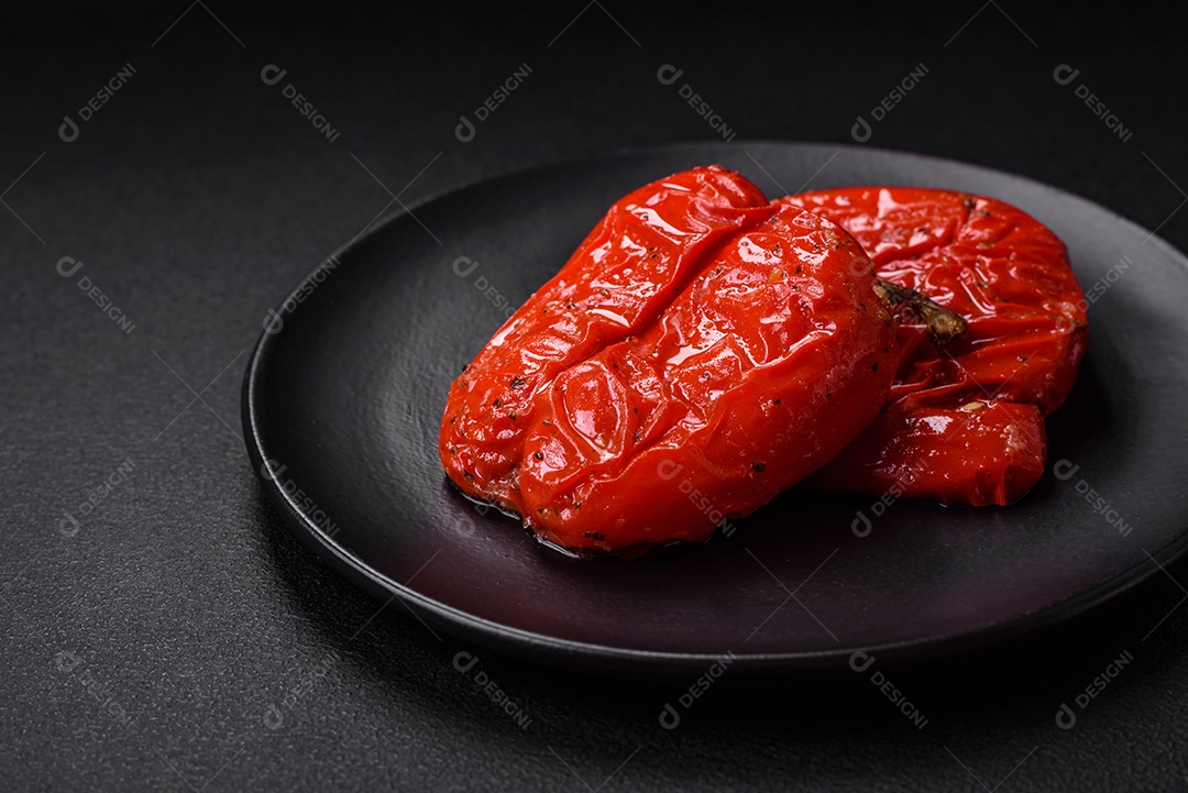 Deliciosos pimentões grelhados com especiarias e ervas em um fundo escuro de concreto