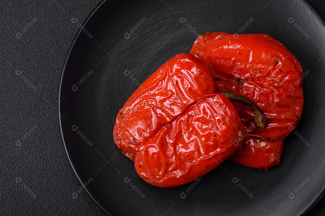 Deliciosos pimentões grelhados com especiarias e ervas em um fundo escuro de concreto