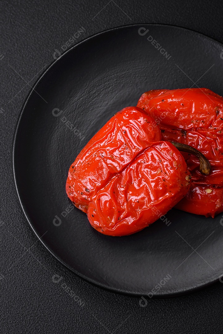 Deliciosos pimentões grelhados com especiarias e ervas em um fundo escuro de concreto
