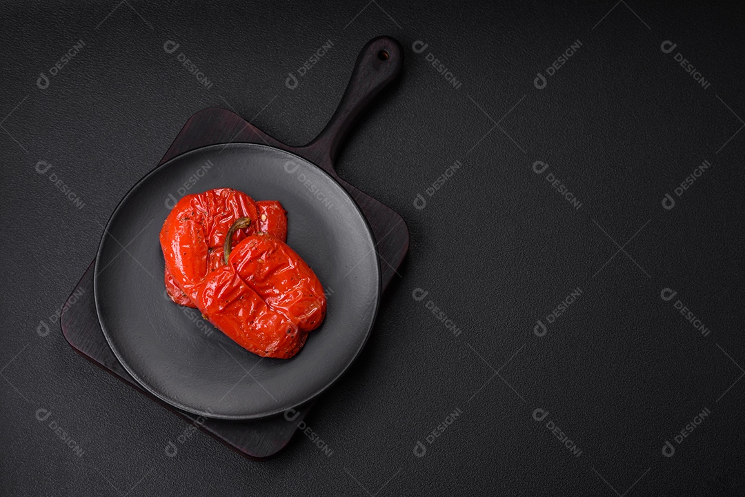 Deliciosos pimentões grelhados com especiarias e ervas em um fundo escuro de concreto