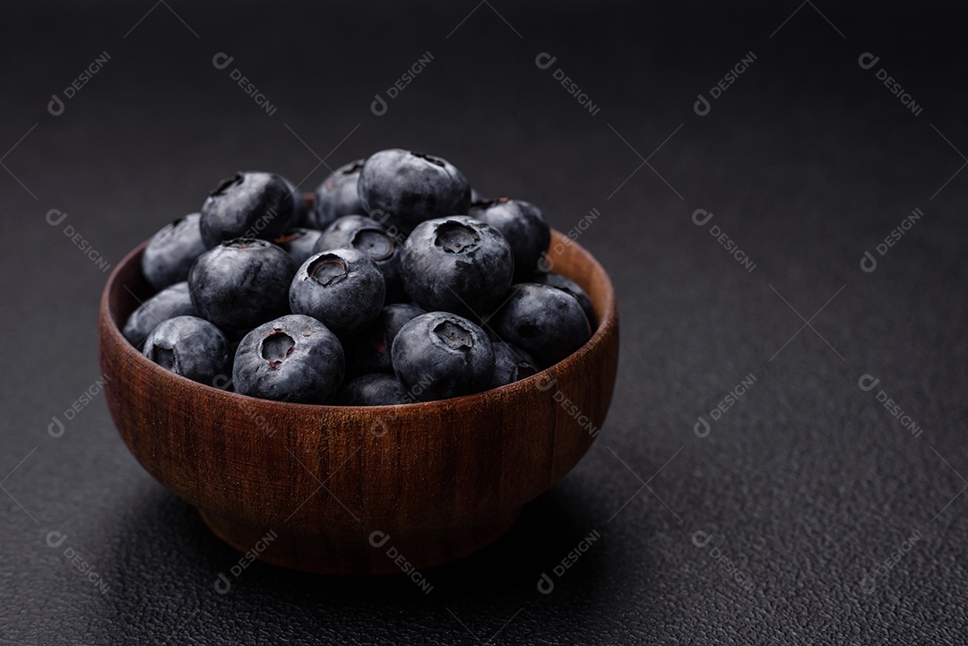 Deliciosos mirtilos doces frescos em uma tigela de cerâmica sobre um fundo escuro de concreto