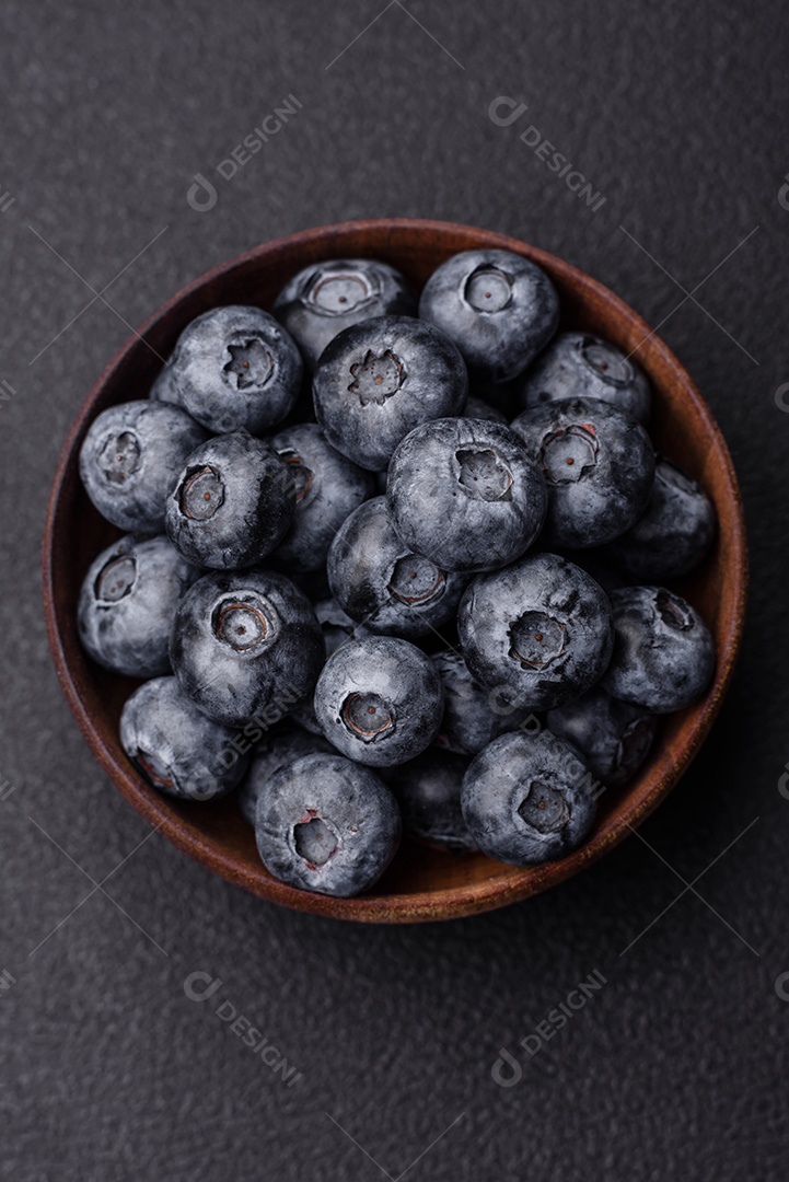 Deliciosos mirtilos doces frescos em uma tigela de cerâmica sobre um fundo escuro de concreto