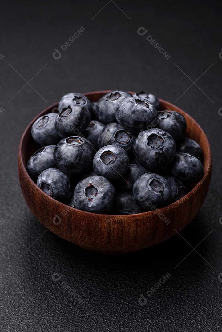 Deliciosos mirtilos doces frescos em uma tigela de cerâmica sobre um fundo escuro de concreto