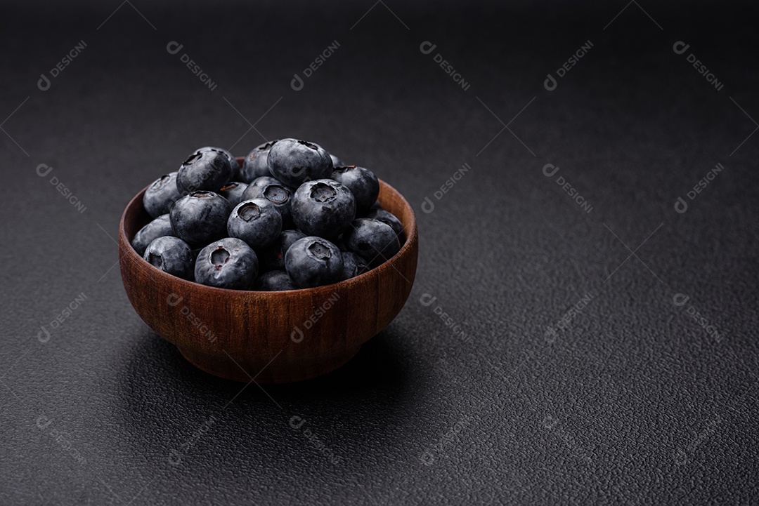 Deliciosos mirtilos doces frescos em uma tigela de cerâmica sobre um fundo escuro de concreto