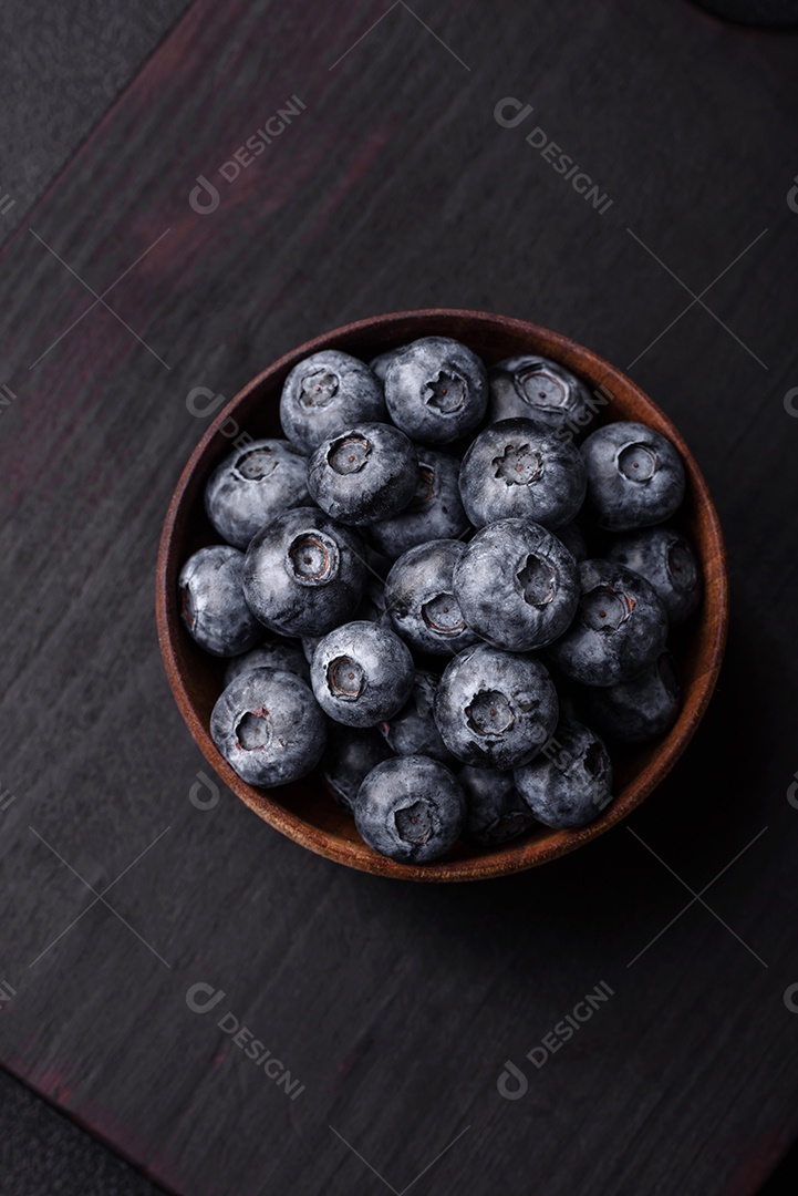 Deliciosos mirtilos doces frescos em uma tigela de cerâmica sobre um fundo escuro de concreto