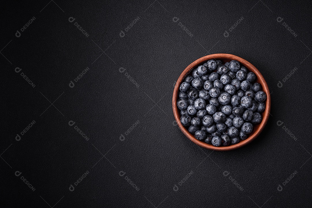 Deliciosos mirtilos doces frescos em uma tigela de cerâmica sobre um fundo escuro de concreto