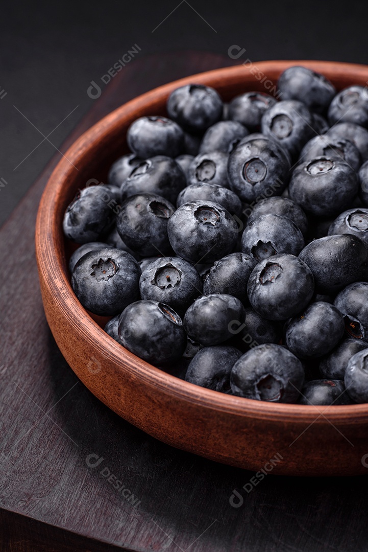 Deliciosos mirtilos doces frescos em uma tigela de cerâmica sobre um fundo escuro de concreto