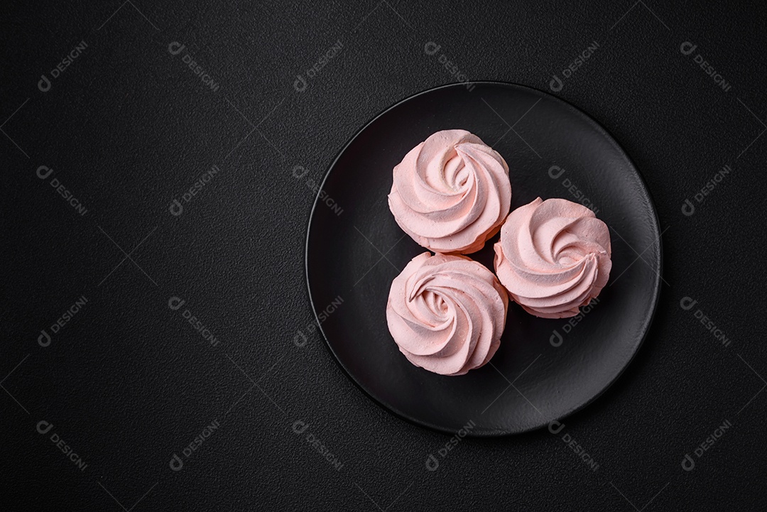 Delicioso marshmallow doce multicolorido em um fundo escuro de concreto. Doces saudáveis ​​para a mesa de jantar