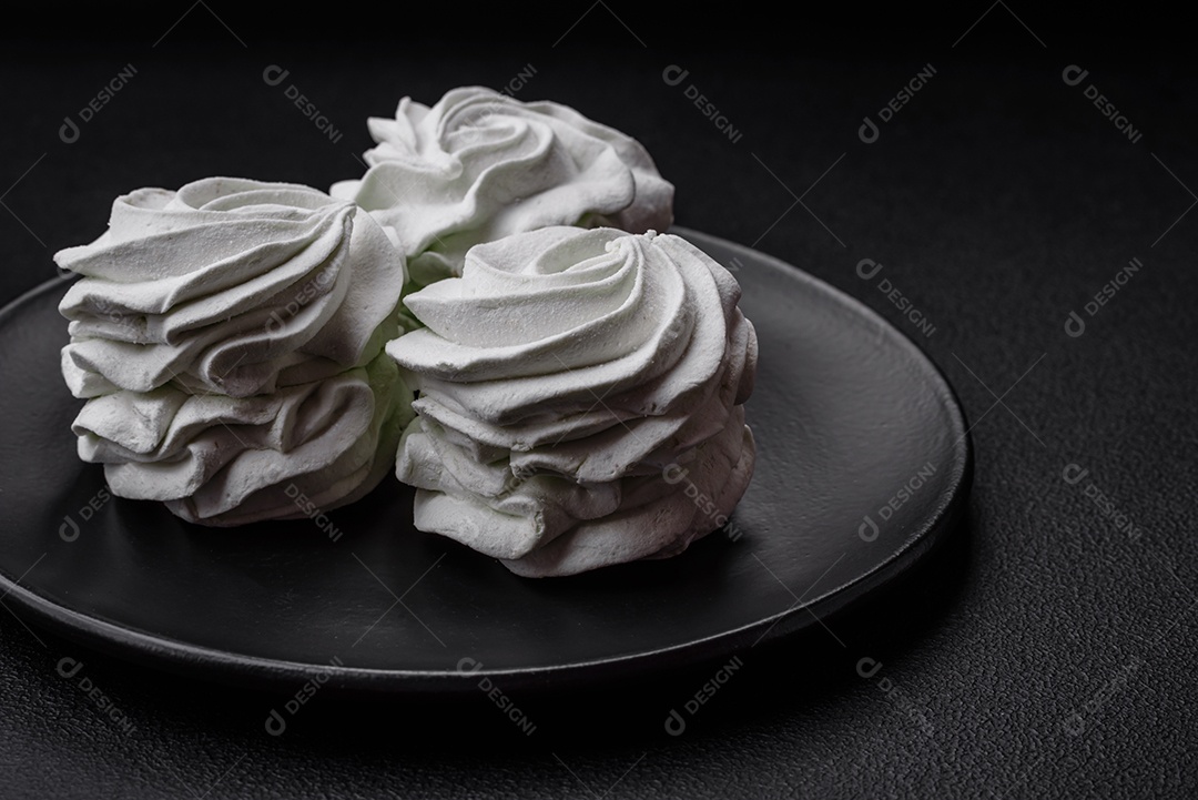 Delicioso marshmallow colorido doce em um fundo escuro de concreto. Doces saudáveis ​​para a mesa de jantar