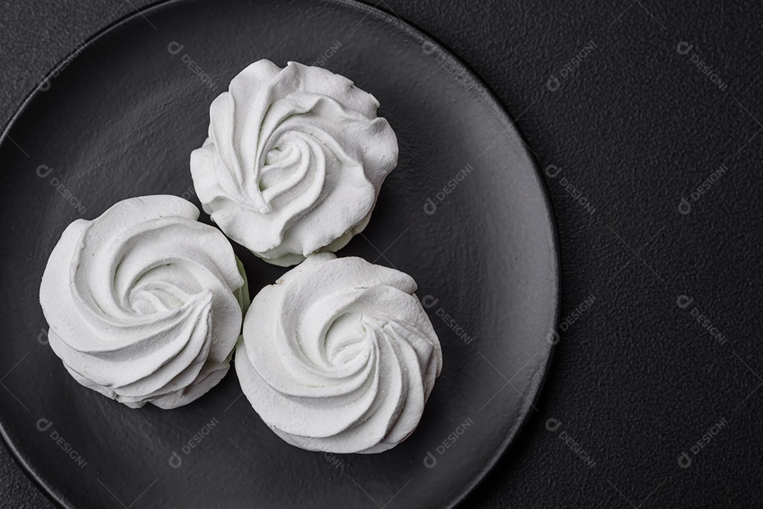 Delicioso marshmallow colorido doce em um fundo escuro de concreto. Doces saudáveis ​​para a mesa de jantar