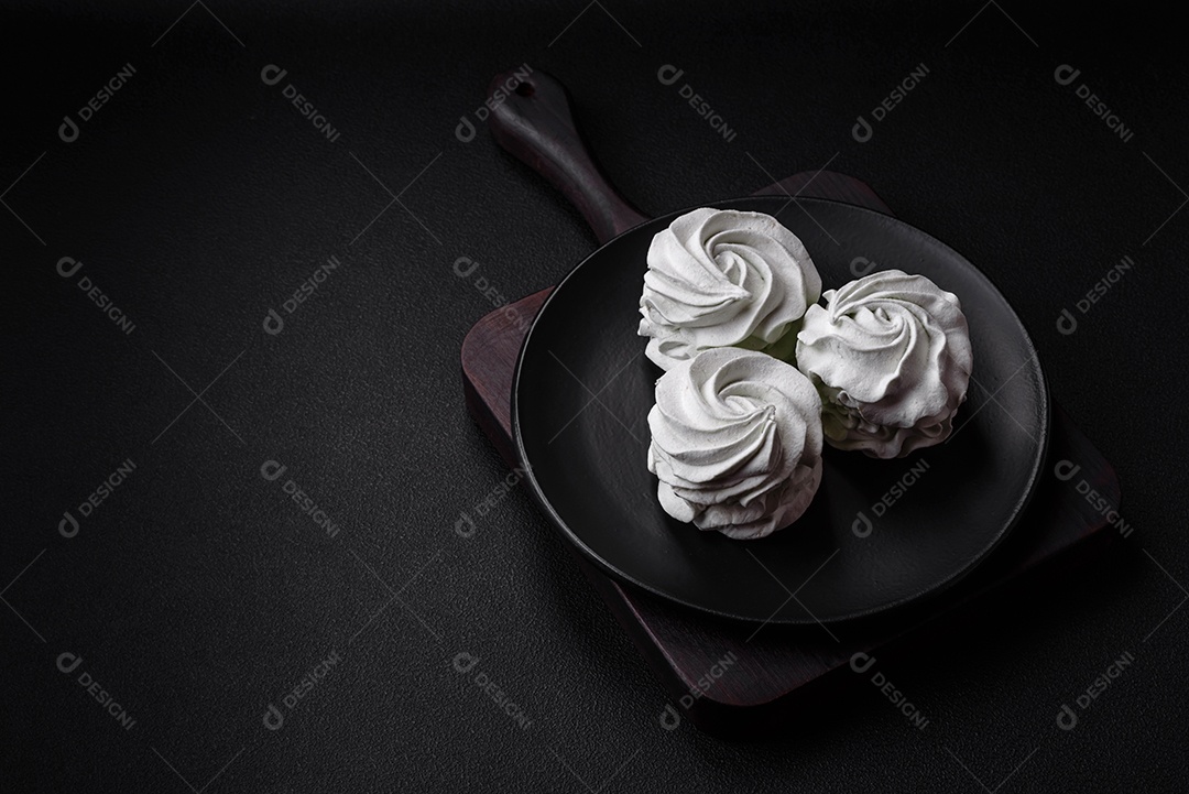 Delicioso marshmallow colorido doce em um fundo escuro de concreto. Doces saudáveis ​​para a mesa de jantar