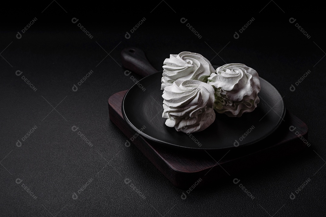 Delicioso marshmallow colorido doce em um fundo escuro de concreto. Doces saudáveis ​​para a mesa de jantar