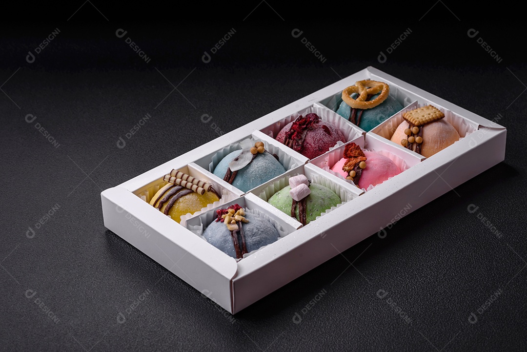 Deliciosas sobremesas mochi coloridas ou sorvete com massa de arroz e coberturas sobre um fundo escuro de concreto