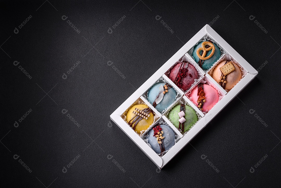 Deliciosas sobremesas mochi coloridas ou sorvete com massa de arroz e coberturas sobre um fundo escuro de concreto