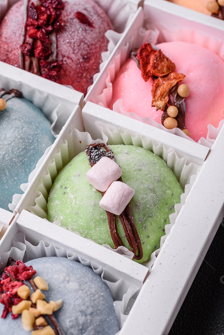 Deliciosas sobremesas mochi coloridas ou sorvete com massa de arroz e coberturas sobre um fundo escuro de concreto