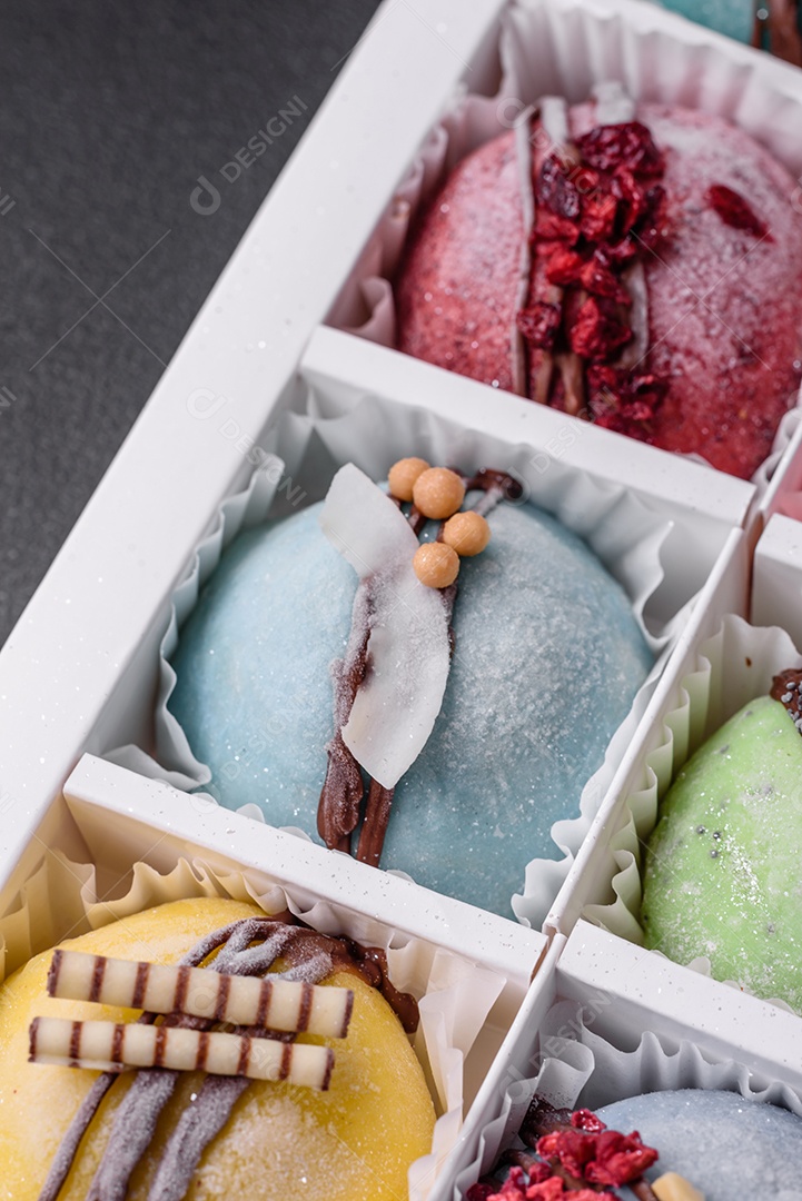 Deliciosas sobremesas mochi coloridas ou sorvete com massa de arroz e coberturas sobre um fundo escuro de concreto