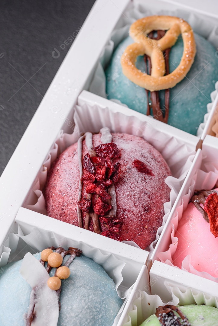 Deliciosas sobremesas mochi coloridas ou sorvete com massa de arroz e coberturas sobre um fundo escuro de concreto