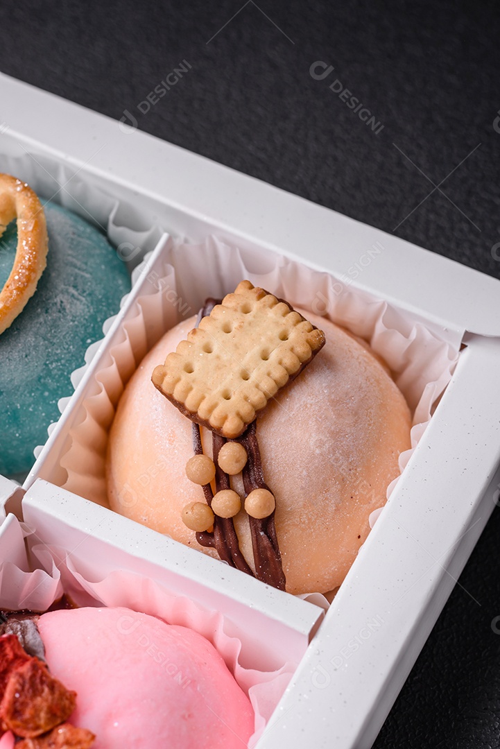 Deliciosas sobremesas mochi coloridas ou sorvete com massa de arroz e coberturas sobre um fundo escuro de concreto