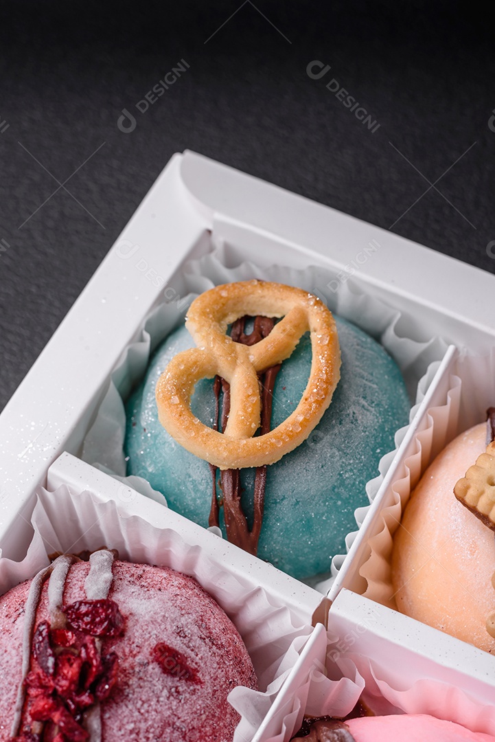 Deliciosas sobremesas mochi coloridas ou sorvete com massa de arroz e coberturas sobre um fundo escuro de concreto