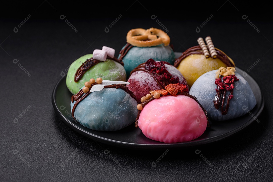 Deliciosas sobremesas mochi coloridas ou sorvete com massa de arroz e coberturas sobre um fundo escuro de concreto