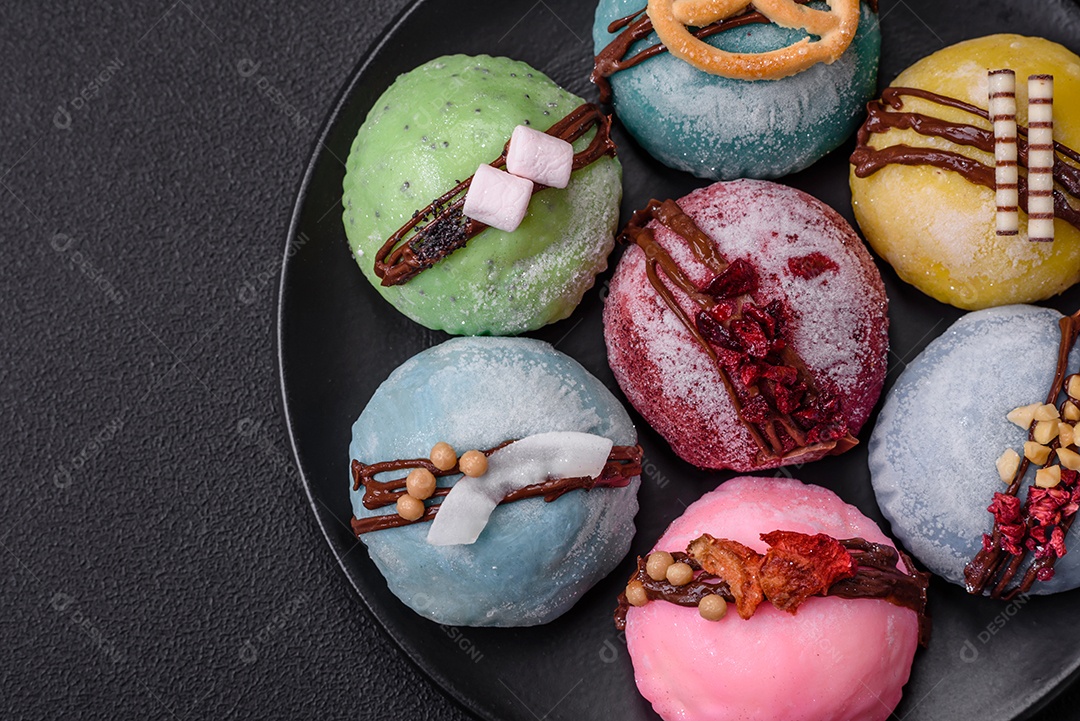 Deliciosas sobremesas mochi coloridas ou sorvete com massa de arroz e coberturas sobre um fundo escuro de concreto