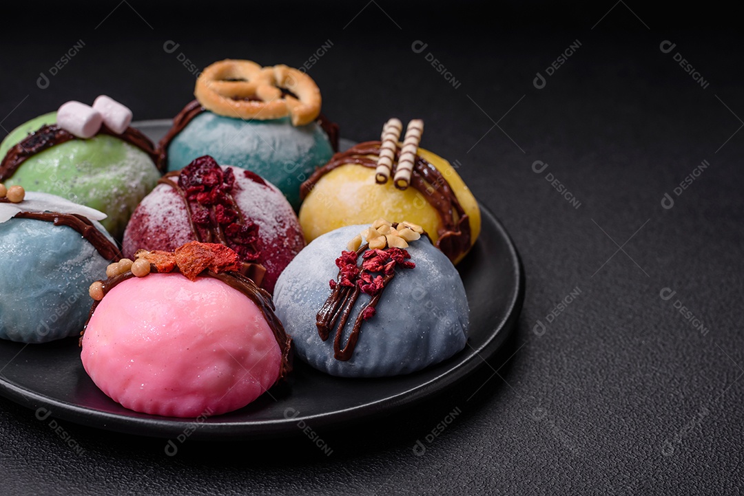 Deliciosas sobremesas mochi coloridas ou sorvete com massa de arroz e coberturas sobre um fundo escuro de concreto