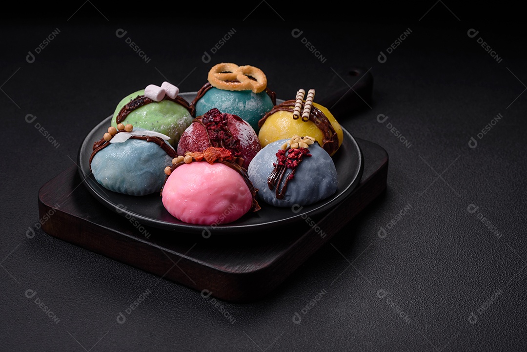 Deliciosas sobremesas mochi coloridas ou sorvete com massa de arroz e coberturas sobre um fundo escuro de concreto