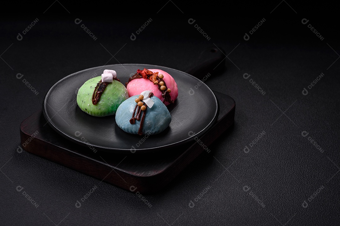 Deliciosas sobremesas mochi coloridas ou sorvete com massa de arroz e coberturas sobre um fundo escuro de concreto