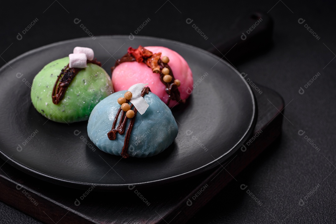 Deliciosas sobremesas mochi coloridas ou sorvete com massa de arroz e coberturas sobre um fundo escuro de concreto