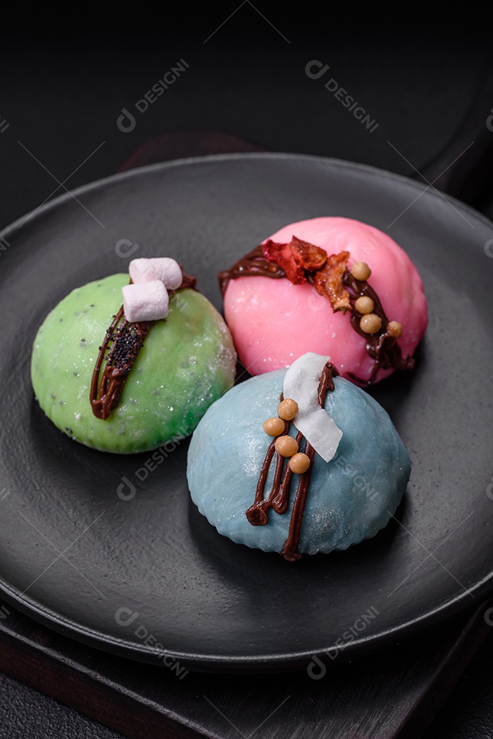 Deliciosas sobremesas mochi coloridas ou sorvete com massa de arroz e coberturas sobre um fundo escuro de concreto