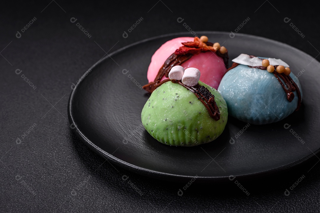 Deliciosas sobremesas mochi coloridas ou sorvete com massa de arroz e coberturas sobre um fundo escuro de concreto