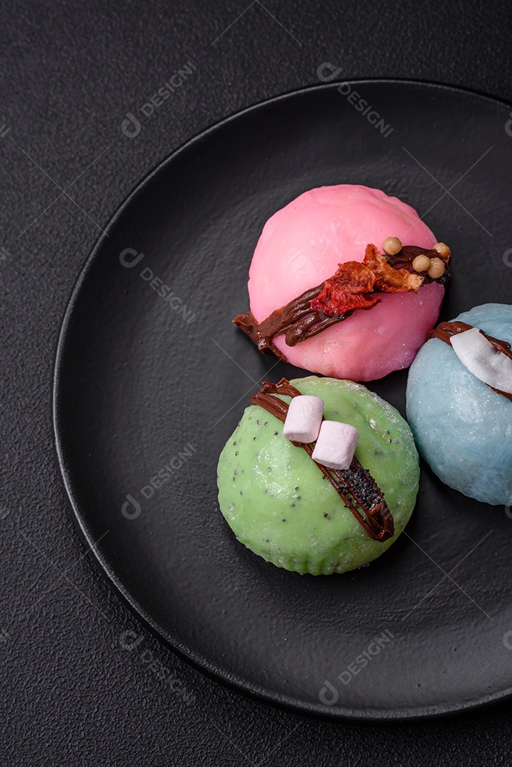 Deliciosas sobremesas mochi coloridas ou sorvete com massa de arroz e coberturas sobre um fundo escuro de concreto