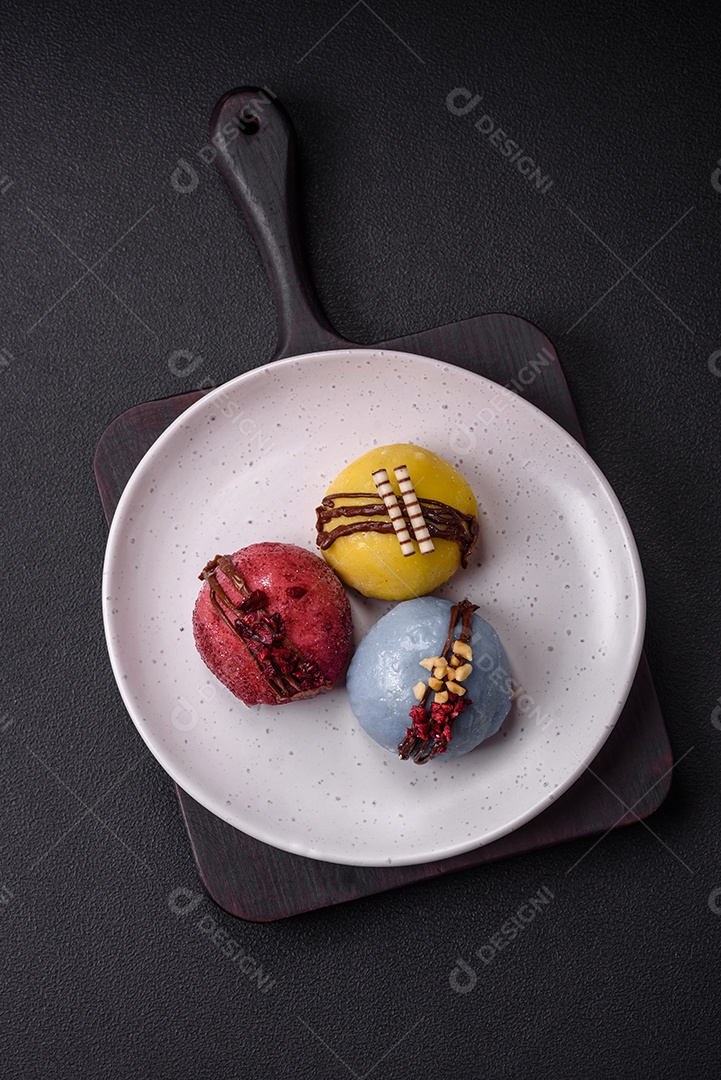 Deliciosas sobremesas mochi coloridas ou sorvete com massa de arroz e coberturas sobre um fundo escuro de concreto