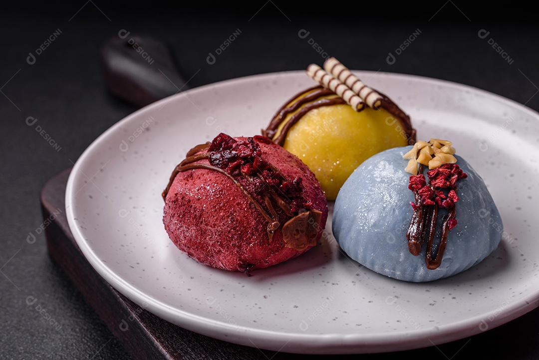 Deliciosas sobremesas mochi coloridas ou sorvete com massa de arroz e coberturas sobre um fundo escuro de concreto