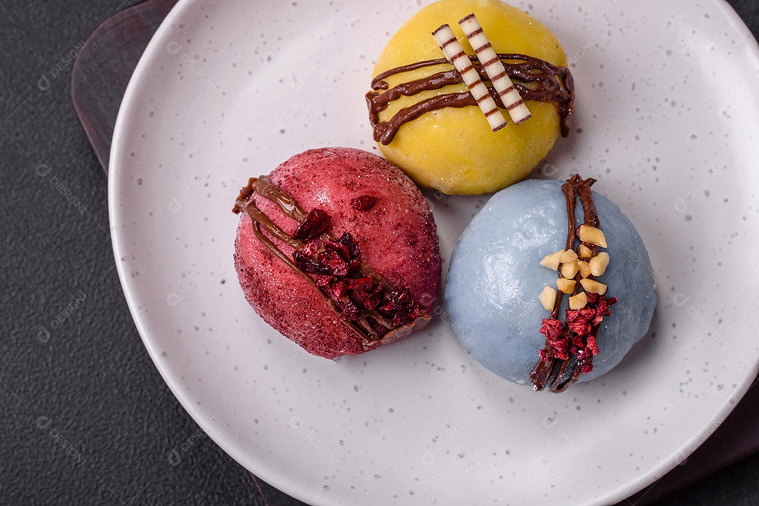 Deliciosas sobremesas mochi coloridas ou sorvete com massa de arroz e coberturas sobre um fundo escuro de concreto