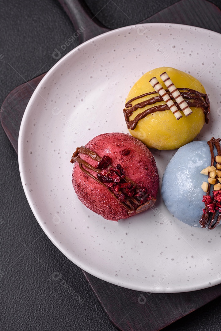 Deliciosas sobremesas mochi coloridas ou sorvete com massa de arroz e coberturas sobre um fundo escuro de concreto