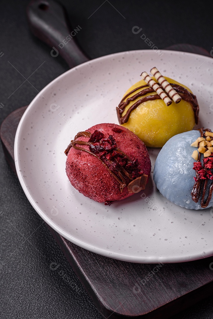 Deliciosas sobremesas mochi coloridas ou sorvete com massa de arroz e coberturas sobre um fundo escuro de concreto
