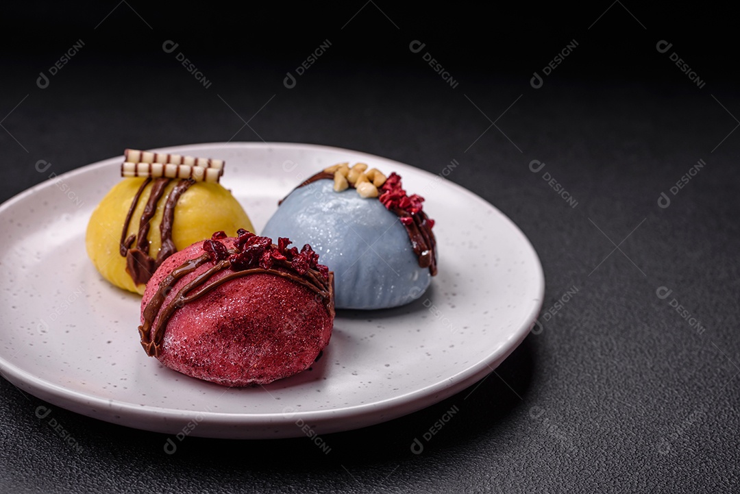 Deliciosas sobremesas mochi coloridas ou sorvete com massa de arroz e coberturas sobre um fundo escuro de concreto