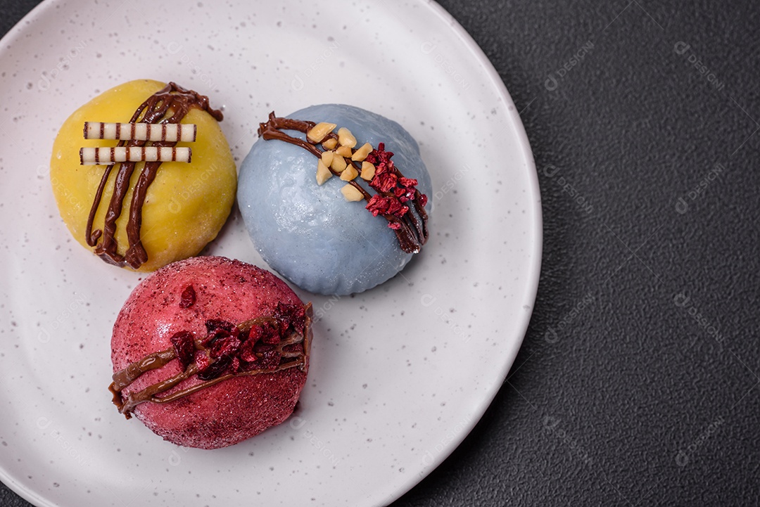 Deliciosas sobremesas mochi coloridas ou sorvete com massa de arroz e coberturas sobre um fundo escuro de concreto