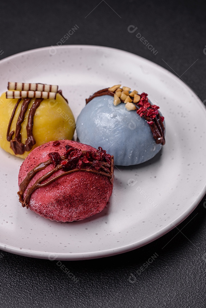 Deliciosas sobremesas mochi coloridas ou sorvete com massa de arroz e coberturas sobre um fundo escuro de concreto