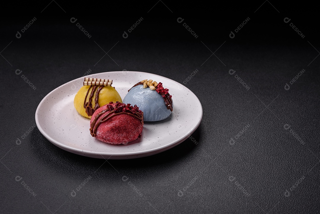 Deliciosas sobremesas mochi coloridas ou sorvete com massa de arroz e coberturas sobre um fundo escuro de concreto