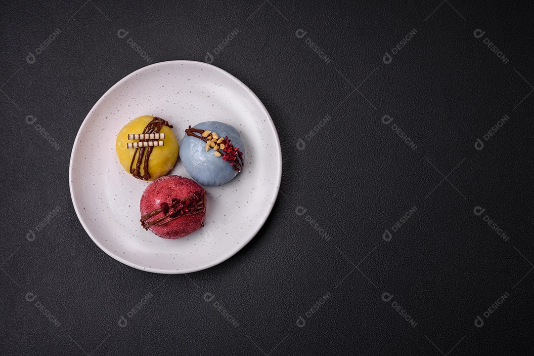 Deliciosas sobremesas mochi coloridas ou sorvete com massa de arroz e coberturas sobre um fundo escuro de concreto