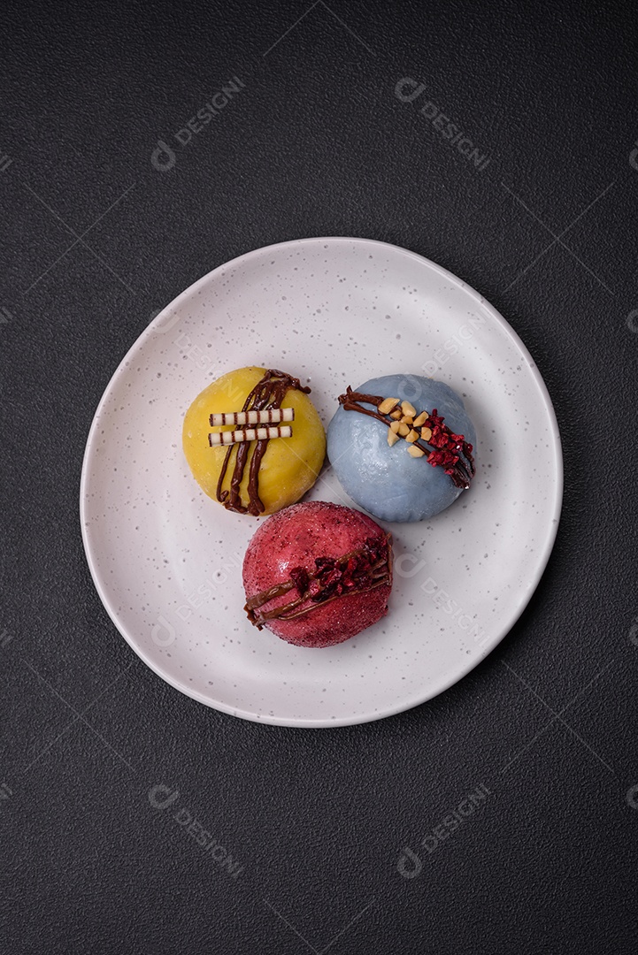 Deliciosas sobremesas mochi coloridas ou sorvete com massa de arroz e coberturas sobre um fundo escuro de concreto