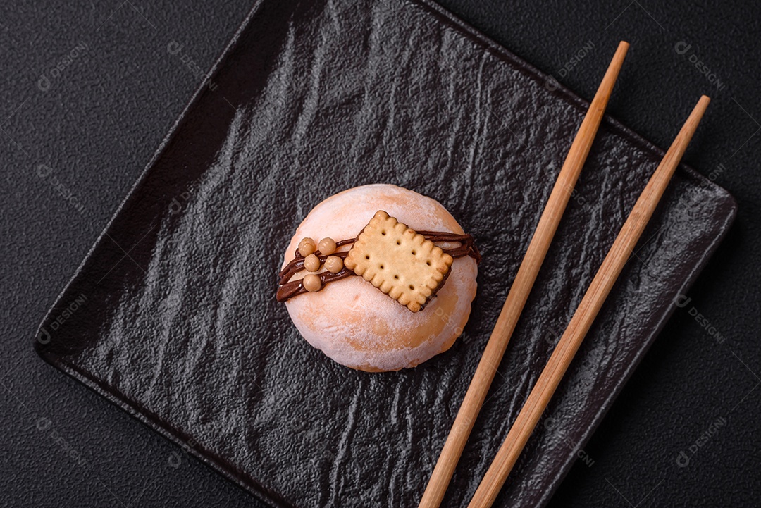 Deliciosas sobremesas mochi coloridas ou sorvete com massa de arroz e coberturas sobre um fundo escuro de concreto