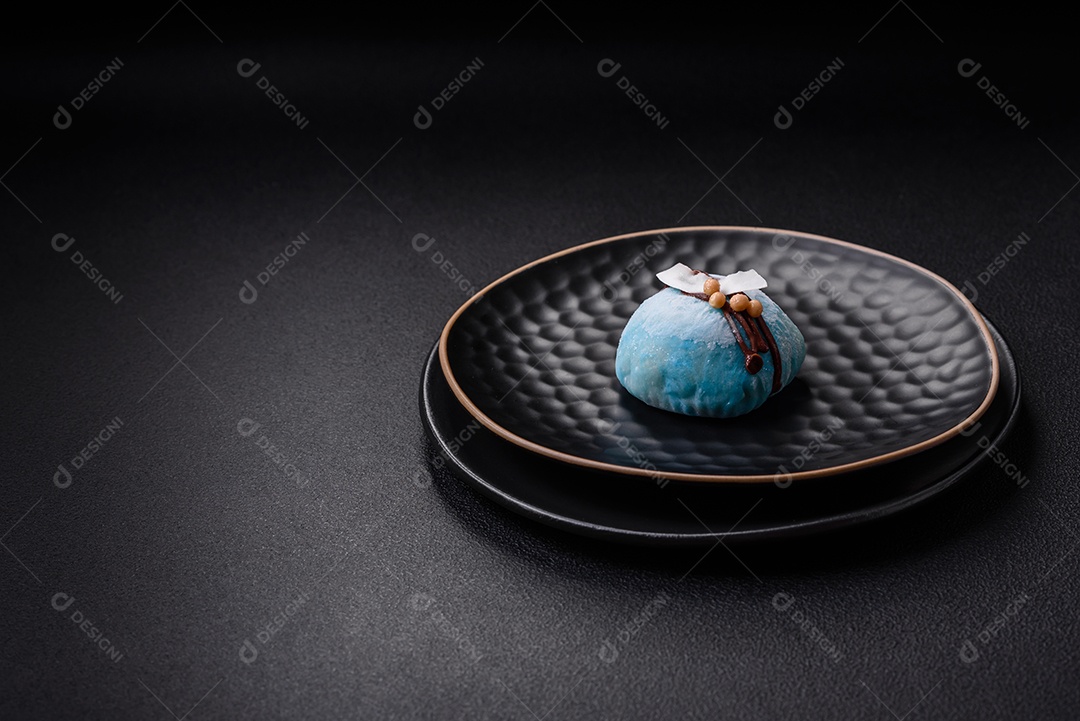 Deliciosas sobremesas mochi coloridas ou sorvete com massa de arroz e coberturas sobre um fundo escuro de concreto