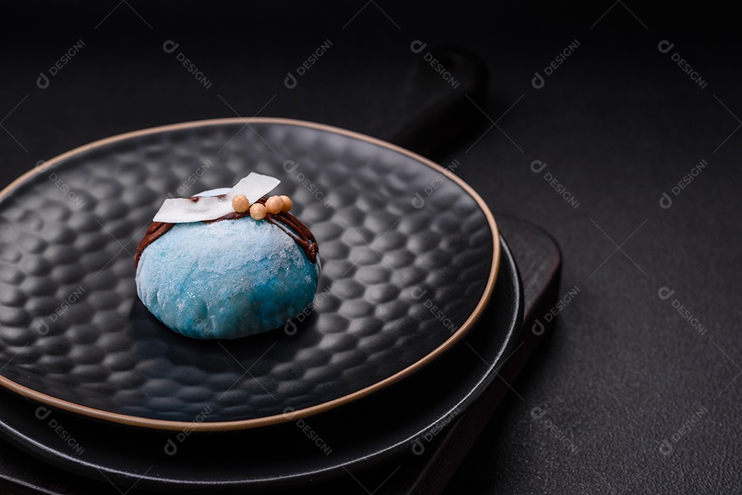 Deliciosas sobremesas mochi coloridas ou sorvete com massa de arroz e coberturas sobre um fundo escuro de concreto