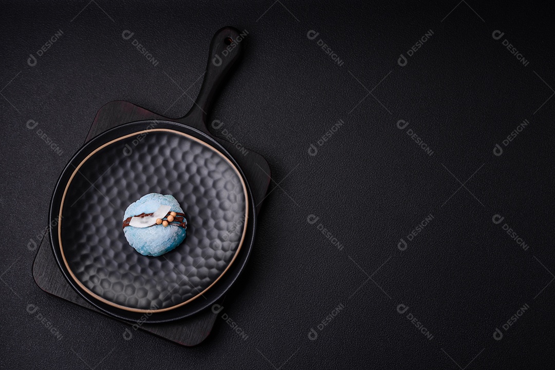 Deliciosas sobremesas mochi coloridas ou sorvete com massa de arroz e coberturas sobre um fundo escuro de concreto